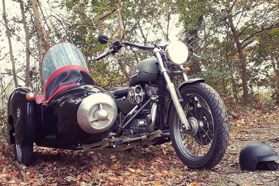 Schwarzes Motorrad mit Beiwagen im Herbstlaub